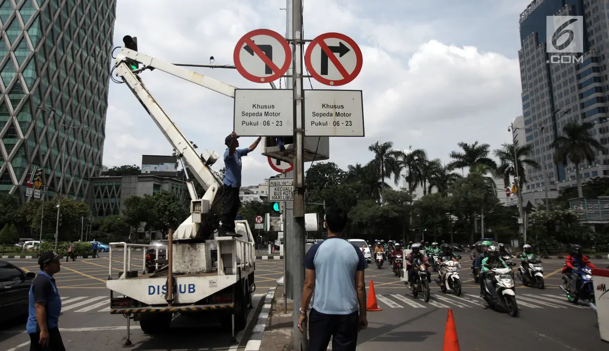 Petugas Dishub menurunkan rambu larangan melintas untuk sepeda motor di Jalan MH Thamrin hingga Jalan Medan Merdeka Barat, Jakarta Pusat, Rabu (10/1). (Liputan6.com/Arya Manggala)