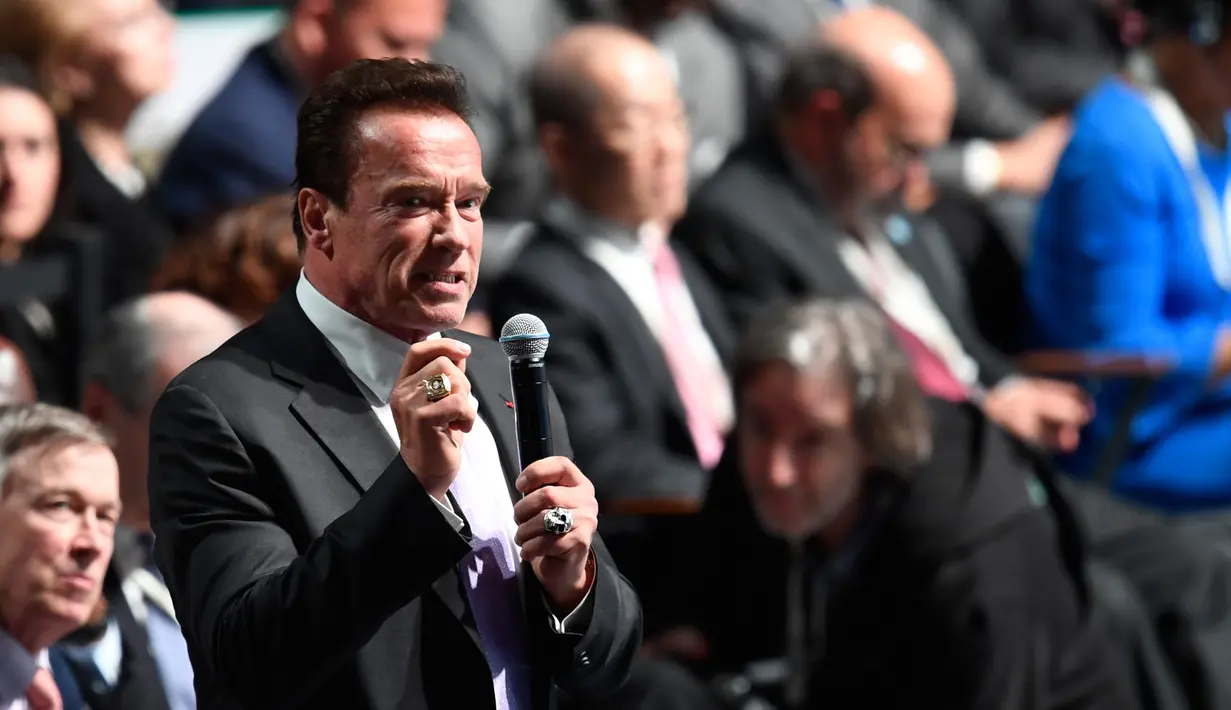 Mantan Gubernur California, Arnold Schwarzenegger berbicara pada forum KTT One Planet Summit di Paris, Selasa (12/12). Aktor AS itu mencuri perhatian dengan dua cincin di jari yang salah satunya bermotif tengkorak warna perak. (AFP PHOTO/Eric FEFERBERG)