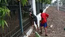 Dua anak menerobos pagar usai menyeberangi rel kereta api di kawasan Lenteng Agung, Jakarta, Selasa (19/3). Tidak adanya JPO menyebabkan warga menerobos pagar besi, meskipun perilaku tersebut berbahaya bagi keselamatan. (Liputan6.com/Immanuel Antonius)