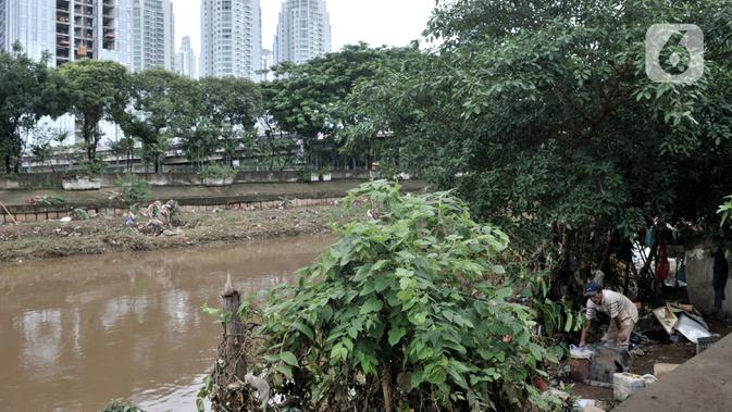 Salah seorang warga bantaran merapikan barang-barang usai banjir merendam gubuk miliknya yang berada di pinggir Kanal Banjir Barat (KBB), Jakarta, Rabu (8/1/2020). (merdeka.com/Iqbal S Nugroho)