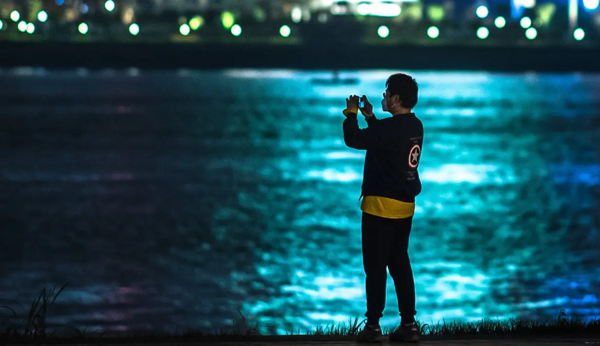 Seorang pria mengabadikan foto di Taman Jiangtan Hankou di Wuhan, Provinsi Hubei, China tengah, pada 26 Maret 2020. Seiring meredanya wabah virus corona (Covid-19), kehidupan di Wuhan berangsur-angsur kembali normal. (Xinhua/Xiao Yijiu)