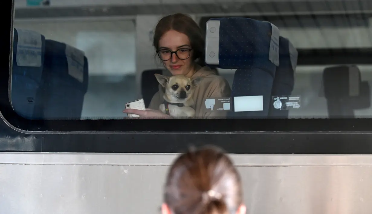 <p>Seorang wanita menunggu dengan anjing peliharaannya di atas kereta meninggalkan stasiun kereta api Kiev menuju negara tetangga Polandia, di Kiev pada 12 Mei 2022. Untuk pertama kalinya sejak awal perang, penghitungan resmi di perbatasan pada 10 Mei menunjukkan 29.000 orang melintasi perbatasan untuk pergi, sedangkan 34.000 orang lainnya melintasi perbatasan untuk kembali ke Ukraina. (Sergei SUPINSKY / AFP)</p>