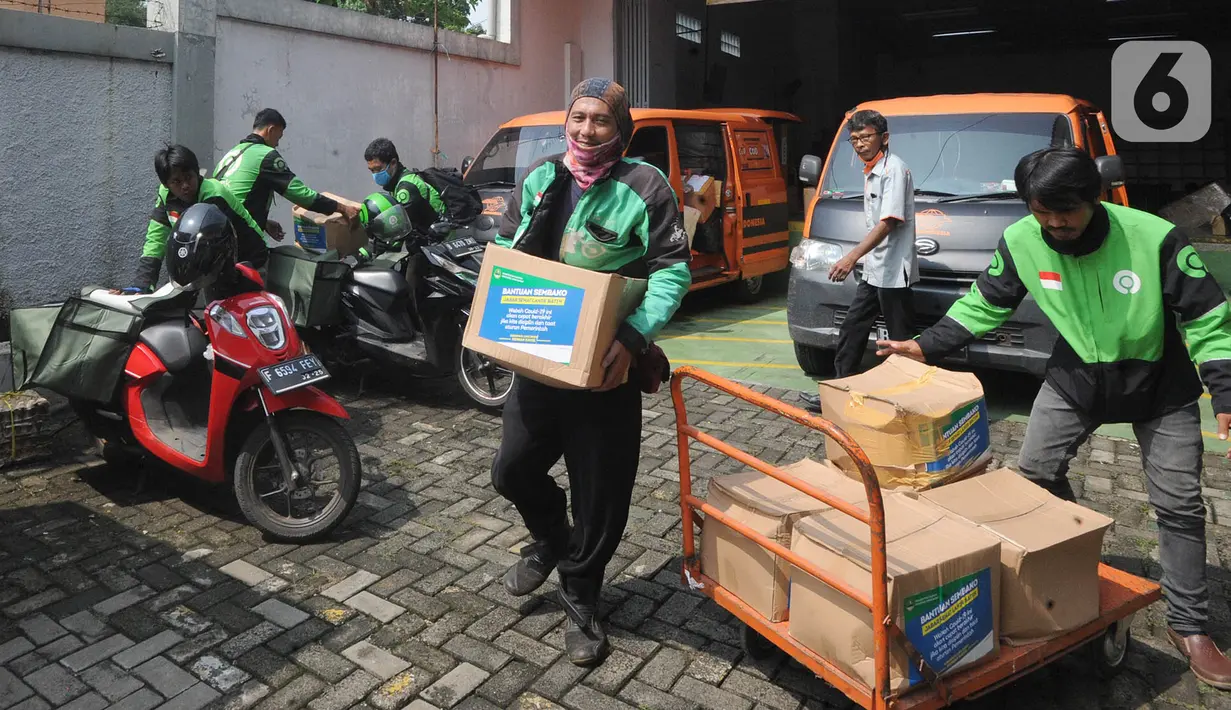 Pengemudi ojek online mengemas bansos untuk warga yang terdampak COVID-19 di Kantor Pos, Cibinong, Bogor, Jawa Barat, Senin (20/4/2020). Bansos khususnya disalurkan di zona merah persebaran yaitu Bogor, Depok, dan Bekasi dengan memberdayakan ojek online. (merdeka.com/Arie Basuki)