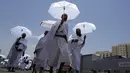 <p>Jemaah haji berjalan sambil memegang payung di kamp tenda Mina, Makkah, Arab Saudi, Senin (26/6/2023). (AP Photo/Amr Nabil)</p>
