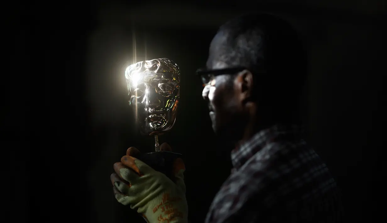 Moulder Rupert Francis berpose memegang topeng BAFTA (British Academy of Film and Television Awards) yang telah selesai  di New Pro Foundries, London, 21 Januari 2020. Topeng piala ini akan dibagikan dalam malam anugerah BAFTA Awards pada 2 Februari mendatang. (JUSTIN TALLIS / AFP)