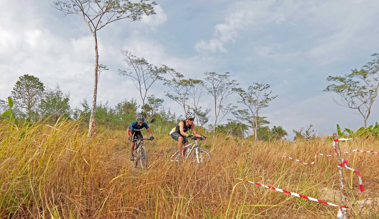 Dua peserta Rhino Cross Triathlon menuruni bukit pada Festival Pesona Tanjung Lesung 2017 di Tanjung Lesung, Banten (24/9/2017). Total jarak tempuh Rhino Cross Triathlon 38 km. (Bola.com/Nicklas Hanoatubun)