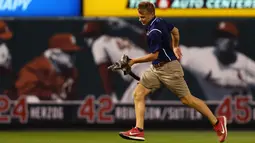 Seorang anggota kru St. Louis Cardinals memindahkan anak kucing dari lapangan keenam inning saat pertandingan melawan Kansas City Royals di Stadion Busch di St. Louis, Missouri (9/8). (Dilip Vishwanat / Getty Images / AFP)