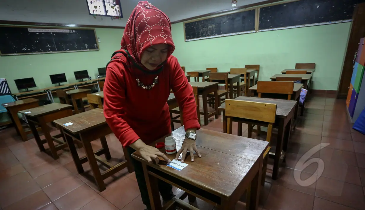 Guru memasang daftar nomor peserta di ruangan kelas SDN 01 Menteng, Jakarta, Minggu (17/5/2015). Sejumlah sekolah melakukan persiapan menjelang Ujian Nasional (UN) jenjang SD/MI yang berlangsung pada 18-20 Mei mendatang. (Liputan6.com/Faizal Fanani)