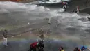 Para demonstran menghindari semprotan water cannon saat bentrok dengan aparat kepolisian di Caracas, Venezuela, (6/4). Banyak yang menilai Keputusan Mahkamah Agung tersebut dinilai sebagai langkah menuju kediktatoran. (AP Photo / Fernando Llano)