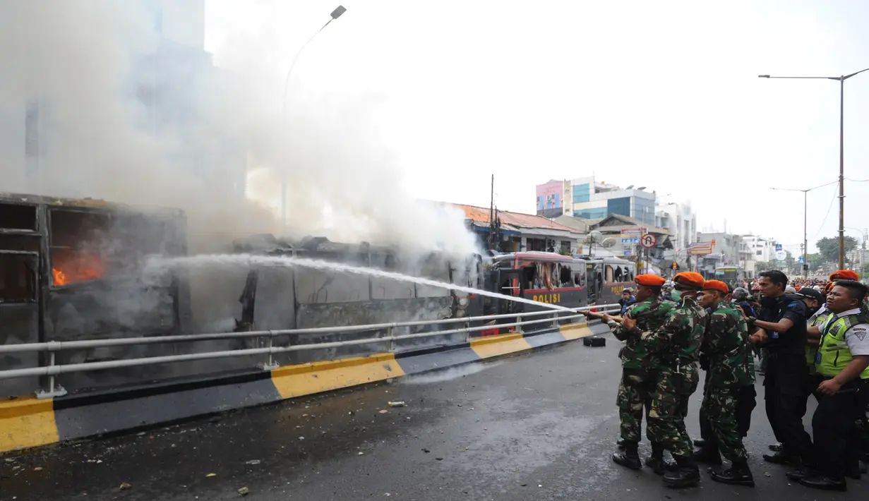 Sejumlah anggota TNI memadamkan api yang membakar dua unit bus polisi di dekat Flyover Slipi, Palmerah, Jakarta Barat, Rabu (22/5/2019). Anggota terus berusaha melakukan pendinginan mengunakan APAR agar api tak kembali menyala. (merdeka.com/Arie Basuki)