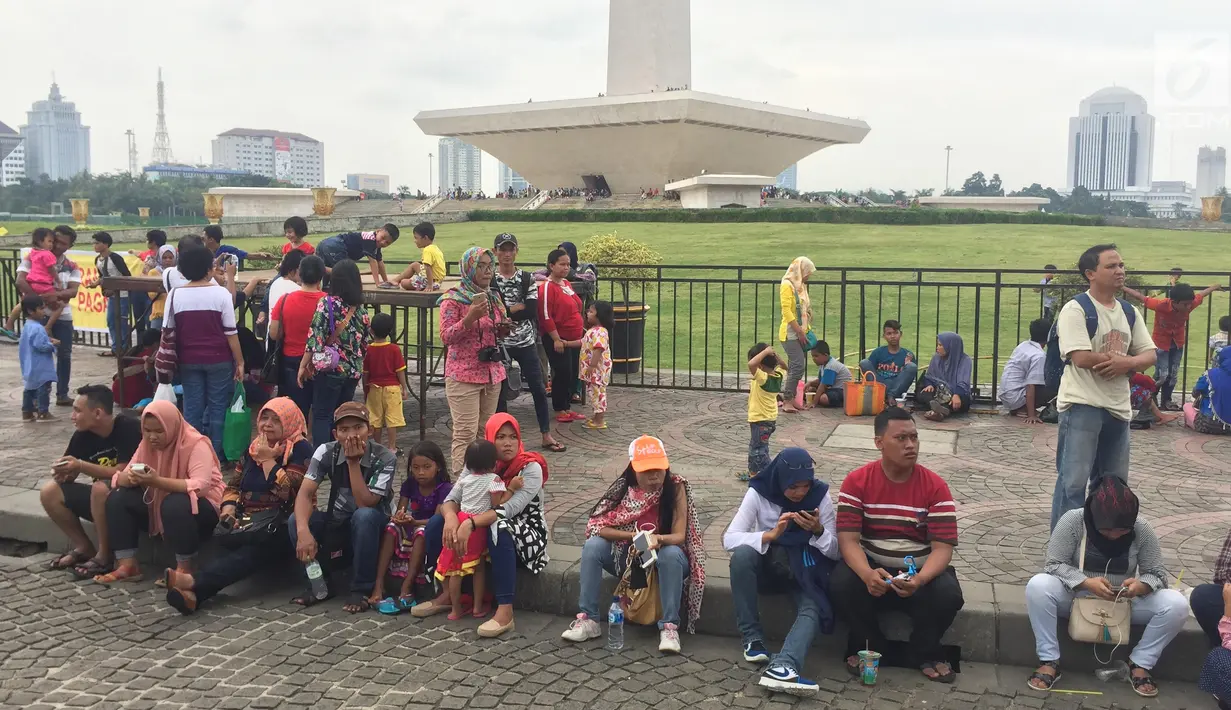 Pengunjung bersantai sambil wisata di kawasan Silang Monumen Nasional (Monas), Jakarta, Sabtu (30/12). Monas adalah salah satu tempat wisata alternatif bagi warga Jakarta dan sekitarnya. (Liputan6.com/Immanuel Antonius)