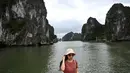 Wisatawan domestik berpose untuk foto di atas kapal di tengah Ha Long Bay, Quang Ninh, Vietnam, (16/5/2020). Seiring dengan meredanya virus corona, Ha Long Bay kawasan yang menjadi situs warisan dunia UNESCO kembali didatangi ratusan wisatawan. (AFP/Manan Vatsyayana)