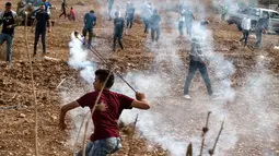 Pengunjuk rasa Palestina menggunakan katapel untuk melemparkan kembali granat gas air mata ke pasukan keamanan Israel saat demonstrasi menentang pembangunan pos terdepan Israel di desa Palestina, Ramallah, Tepi Barat, Kamis (17/10/2019). (JAAFAR ASHTIYEH/AFP)