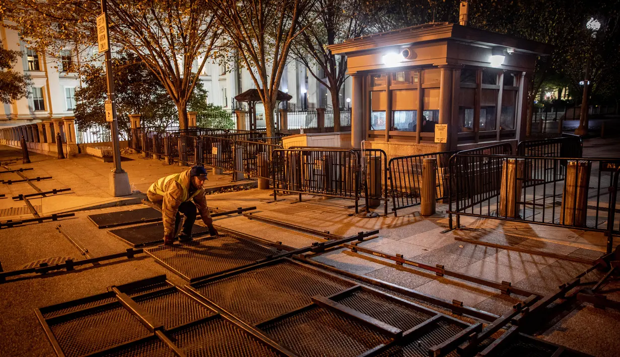 Pekerja mempersiapkan pagar besi untuk dipasang di pintu masuk Gedung Putih mengantisipasi kerusuhan menjelang Pilpres AS di Washington DC, Senin (2/11/2020). Sebagai persiapan kemungkinan ada aksi terorisme atau protes massa, Gedung Putih membangun pagar baru. (Chris McGrath/Getty Images/AFP)