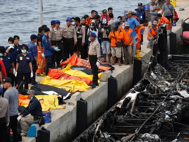 Petugas kepolisian bersama Tim SAR gabungan bersiap mengevakuasi kantong jenazah berisi penumpang kapal Zahro Express yang terbakar, di Pelabuhan Muara Angke, Minggu (1/1). Sedikitnya 23 orang tewas dan 17 lainnya masih hilang. (REUTERS/Darren Whiteside)