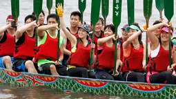 Seorang peserta melambaikan tangan saat mengikuti perlombaan tradisional China, Dragon Boat di Taipei, taiwan, Minggu (28/5). Perlombaan perahu naga ini untuk mengenang kematian penyair Qu Yuan yang tewas tenggelam pada 278 SM. (AP Photo/Chiang Ying-ying)