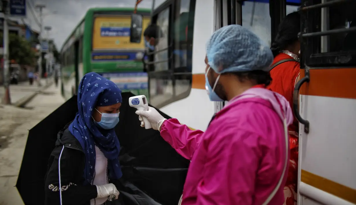 Seorang staf mengukur suhu tubuh penumpang bus di Kathmandu (16/7/2020). Beberapa perusahaan angkutan umum di Lembah Kathmandu mulai mengoperasikan kembali rute mereka untuk pertama kalinya dalam hampir empat bulan setelah menerima persyaratan operasional dari pemerintah. (Xinhua/Sulav Shrestha)
