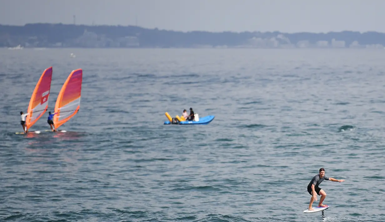 Orang-orang menikmati olahraga air di dekat Pulau Enoshima di pantai Prefektur Kanagawa, barat daya Tokyo (13/8/2019). Enoshima juga akan menjadi tempat olah raga air untuk Olimpiade Musim Panas 2020. (AFP Photo/Charly Triballeau)