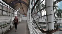 Pejalan kaki saat melewati jembatan penyeberangan orang (JPO) yang berada di Jalan Sudirman, Jakarta, Rabu (17/4). JPO yang berada di tengah gedung-gedung perkantoran ini tidak terlihat terurus dan usang. (Merdeka.com/Iqbal Nugroho)