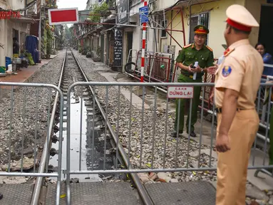 Polisi berjaga dekat barikade rel kereta yang populer sebagai lokasi selfie di Hanoi, Vietnam, Kamis (10/10/2019). Pihak berwenang menutup kafe yang berjajar di pinggir rel kereta tersebut dengan alasan keamanan. (Nhac NGUYEN/AFP)