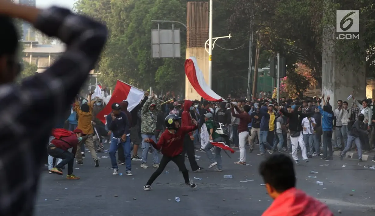 Massa melempar batu ke arah polisi yang membentuk barikade dengan tameng di sekitaran Gedung DPR RI, Jakarta, Senin (30/9/2019). Kericuhan pecah lantaran massa yang kebanyakan terdiri dari pelajar tersebut berusaha masuk ke area depan DPR. (Liputan6.com/Johan Tallo)