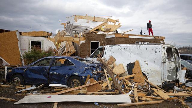 <span>Redzo Beganovic berdiri di atas apartemennya yang hancur diterjang tornado di Bowling Green, Kentucky, Amerika Serikat, 11 Desember 2021. Presiden AS Joe Biden berjanji untuk mengunjungi wilayah yang rusak, tetapi tidak ingin "menghalangi penyelamatan dan pemulihan." (AP Photo/Michael Clubb)</span>