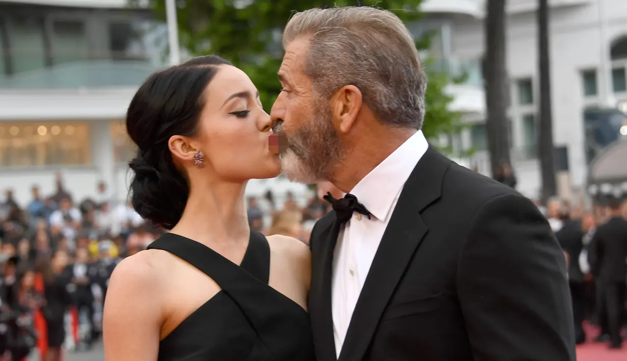 Aktor senior Mel Gibson mencium bibir pacar barunya, Rosalind Ross saat menghadiri acara penutupan Festival Film Cannes, Prancis, 22 Mei 2016.  Seperti yang diketahui, usia Mel Gibson dan kekasih cantiknya terpaut 35 tahun. (Anne-CHRISTINE POUJOULAT/AFP)