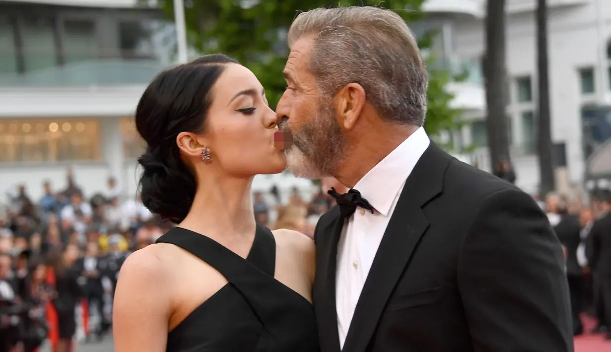 Aktor senior Mel Gibson mencium bibir pacar barunya, Rosalind Ross saat menghadiri acara penutupan Festival Film Cannes, Prancis, 22 Mei 2016.  Seperti yang diketahui, usia Mel Gibson dan kekasih cantiknya terpaut 35 tahun. (Anne-CHRISTINE POUJOULAT/AFP)