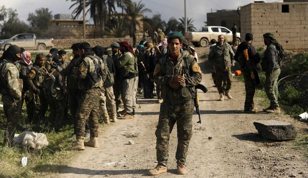 Anggota Syrian Democratic Forces beristirahat saat memburu militan ISIS di kantong terakhir kekhalifahan di Baghouz, Suriah, Selasa (19/2). Sebelumnya, ISIS menguasai area seluas Inggris Raya dan memerintah lebih dari 10 juta orang. (Delil souleiman/AFP)