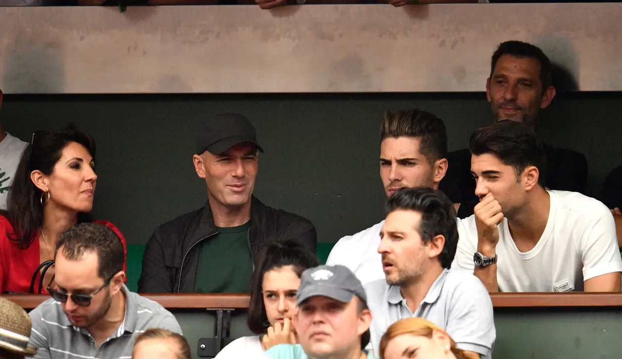 Zinedine Zidane ditemani istri, Veronique, dan anaknya, Luca  serta Enzo menyaksikan final Prancis Terbuka 2018 di Roland Garros, Minggu (10/6). Partai puncak itu mempertemukan antara Rafael Nadal dan Dominic Thiem. (AFP/CHRISTOPHE SIMON)