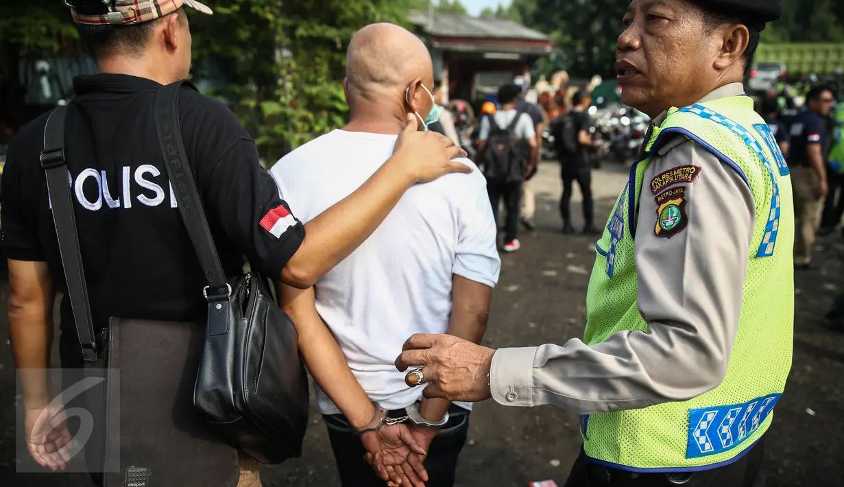 Seorang warga diciduk petugas Satuan narkoba Polres Jakut pada penggerebekan di Kampung Bahari, Tanjung Priok, Jakarta, Kamis (25/8). Penggerebekan melibatkan ratusan personel gabungan. (Liputan6.com/Faizal Fanani)