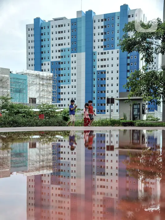 Anak-anak penghuni Rusun Nagrak bermain dekat tower yang difungsikan sebagai pusat karantina WNI atau pekerja migran Indonesia, Cilincing, Jakarta, Rabu (22/12/2021). Kepala BNPB Suharyanto mengungkapkan, Rusun Nagrak akan jadi pusat karantina selama 10 hari ke depan. (merdeka.com/Iqbal S. Nugroho)