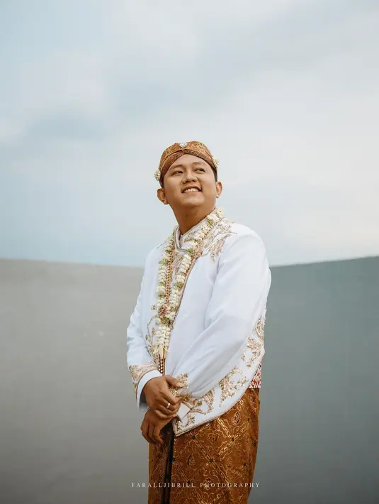Denny tampak gagah dalam balutan beskap putih dengan aksen bordir dan payet. Penampilannya dilengkapi dengan blangkon.