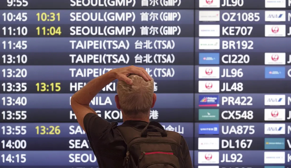 Salah satu wisatawan asing berdiri di depan papan informasi penerbangan setibanya di Bandara Internasional Haneda, Tokyo, Selasa (11/10/2022).  Langkah Jepang untuk menghapus sebagian besar pembatasan pada turis asing akhirnya mulai diterapkan ketika gelombang pandemi paling mematikan di negara itu surut. (AP Photo/Eugene Hoshiko)