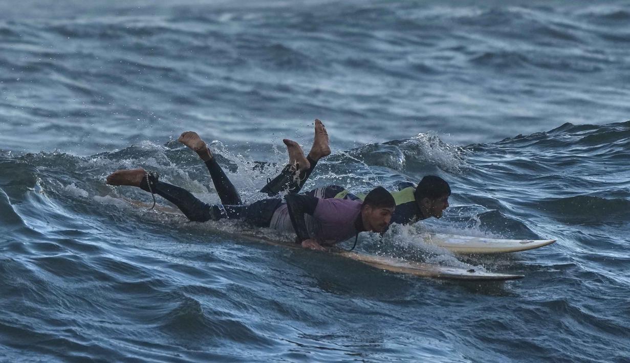 Bagi warga Palestina di Gaza, laut dan berselancar dianggap sebagai simbol kebebasan dan harapan di tengah keterbatasan ruang gerak akibat blokade dan konflik. Tampak dalam foto, warga Palestina, Khalil Abu Jayyab (kanan) dan Tahseen Abu Assi berselancar di pantai Kota Gaza, Minggu, 28 Desember 2025. (AP Photo/Jehad Alshrafi)