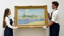 Staf memegang lukisan 'Vétheuil' karya Claude Monet di Sotheby's, London, Inggris, 22 Juni 2022. Lukisan yang akan dilelang pada 29 Juni 2022 itu diperkirakan memiliki harga 10-15 juta pound. (AP Photo /Alberto Pezzali)