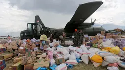 Prajurit TNI dibantu tentara Amerika Serikat mendistribusikan bantuan logistik yang tiba di Bandara Mutiara Sis Al-Jufri, Palu, Sulawesi Tengah, Minggu (7/10). Bantuan asing tiba menggunakan pesawat Hercules. (Liputan6.com/Fery Pradolo)