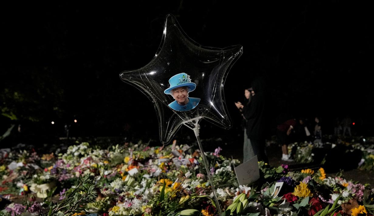 Foto Ratu Elizabeth II ditempatkan di dalam balon saat orang-orang membawa karangan bunga di Green Park London, Senin (12/9/2022). Ratu Elizabeth II meninggal pada usia 96 tahun di Kastil Balmoral, Skotlandia.  Dia adalah penguasa terlama sepanjang sejarah Britania Raya yaitu 70 tahun 214 hari. (AP Photo/Andreea Alexandru)