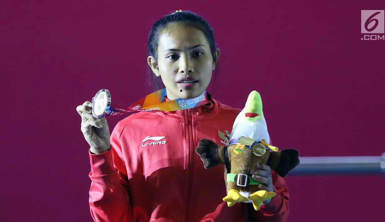 Atlet Para Powerlifting Indonesia, Ni Nengah Widiasih memperlihatkan medali perak Womens Up to 41.00kg Asian Para Games 2018 di Jakarta, Minggu (7/10). Ni Nengah Widiasih berhasil melakukan total angkatan 97 kg. (Liputan6.com/Helmi Fithriansyah)