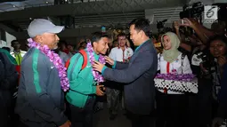 Menpora, Imam Nahrawi mengalungkan bunga kepada pemain Timnas Indonesia U-16, Fadillah Nur Rahman saat penyambutan di Bandara Soetta, Tangerang, Kamis (15/2). Timnas U-16 berhasil menjuarai turnamen Jenesys di Jepang. (Liputan6.com/Helmi Fithriansyah)