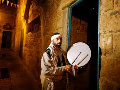 Michel Ayoub, seorang Kristen Arab-Israel, ketika membangunkan kaum muslim untuk melaksanakan sahur di Arce, Israel, Senin (20/6). Michel Ayoub sudah bertahun-tahun membangunkan sahur kaum muslim di sekitarnya selama Ramadan. (REUTERS/Ammar Awad)