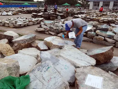 Seorang pedagang memeriksa batu giok dalam bentuk bongkahan yang ditampilkan selama Gems Emporium di Naypyitaw, Myanmar, Selasa (13/11). Acara tahunan tersebut dimulai pada Senin dan akan berlangsung hingga 17 November 2018. (AP/Aung Shine Oo)