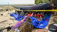 Pengungsi Rohingya berkumpul dalam tenda di pantai di Pulau Sabang, Provinsi Aceh, Indonesia, Minggu (3/12/2023). Lebih dari 100 pengungsi Rohingya, termasuk perempuan dan anak-anak, mendarat di pantai Aceh pada tanggal 2 Desember 2023 dini hari. (CHAIDEER MAHYUDDIN/AFP)