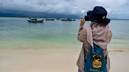 Pulau ini terletak di Desa Pulau Baguk, kecamatan Pulau Banyak, Aceh. Tampak dalam foto seorang wanita mengambil foto di Pulau Panjang, yang pernah menjadi objek sengketa batas pulau antara Aceh dan Sumatra Utara, di Singkil, Provinsi Aceh bagian selatan, pada Rabu 12 November 2025. (CHAIDEER MAHYUDDIN/AFP)