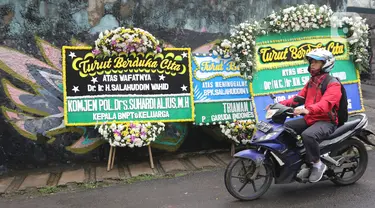 Pengendara melintas dekat karangan bunga duka cita atas meninggalnya KH Salahuddin Wahid atau Gus Sholah di rumah duka Mampang Prapatan, Jakarta, Senin (3/2/2020). Ulama yang juga adik kandung Presiden ke-4 RI Gus Dur itu meninggal dunia pada hari Minggu (2/2/2020). (Liputan6.com/Herman Zakharia)