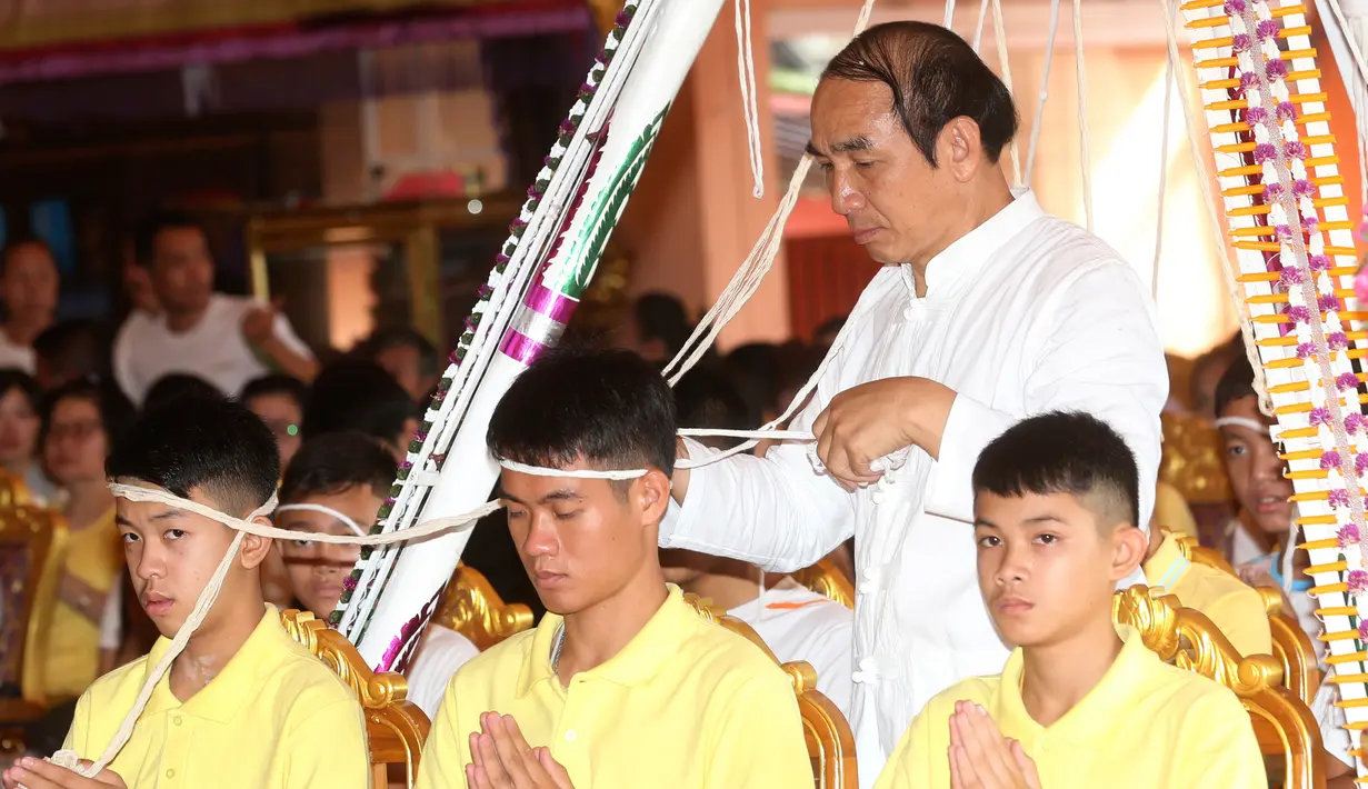 Pelatih tim sepak bola remaja Thailand, Ekkapol Janthawong (tengah) bersama anak asuhnya mengikuti ritual di Distrik Mae Sai, Chiang Rai, Kamis (19/7). Ritual ini diyakini memperpanjang hidup serta membersihkan mereka dari bahaya. (AP Photo/Sakchai Lalit)