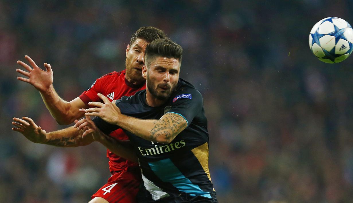  Pemain Bayern Munich Xabi Alonso berebut bola dengan pemain Arsenal Olivier Giroud pada lanjutan Liga Champion di Allianz Arena, Munich, Jerman, Kamis (5/11/15) dini hari. Bayern menang 5-1. (Reuters / Michael Dalder)