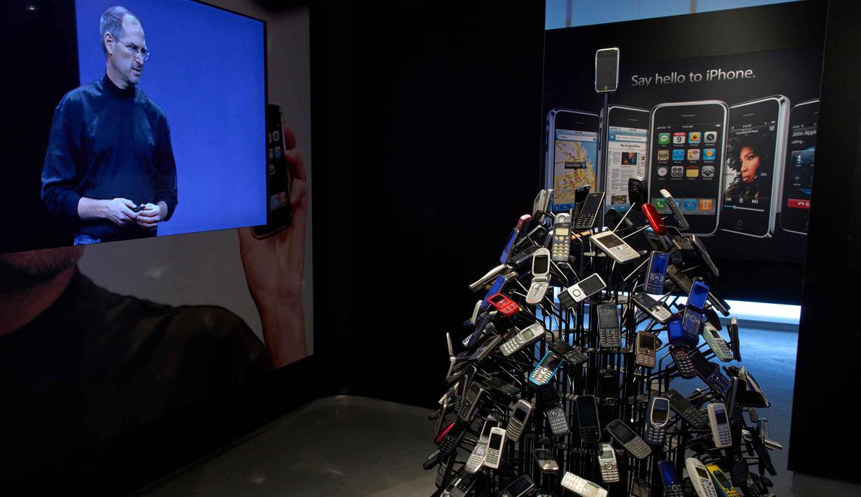 Untuk diketahui, Apple didirikan pada 1 April 1976 dengan semangat untuk menantang kebiasaan lama dan menghadirkan cara baru dalam memanfaatkan teknologi. Tampak dalam foto, iPhone dan video mantan CEO Apple Steve Jobs terlihat di Museum Apple baru yang menelusuri 50 tahun inovasi merek ikonik tersebut, di Utrecht, Belanda, Rabu, 1 April 2026. (AP Photo/Peter Dejong)