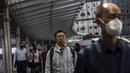 Seorang pria (tengah) berjalan melalui kawasan pusat bisnis di Hong Kong (1/3/2023). Pencabutan penggunaan masker sebagai salah satu upaya Hong Kong untuk menarik dan menyambut wisatawan dan pembisnis pasca aturan ketat hampir selama tiga tahun. (AFP/Isaac Lawrence)