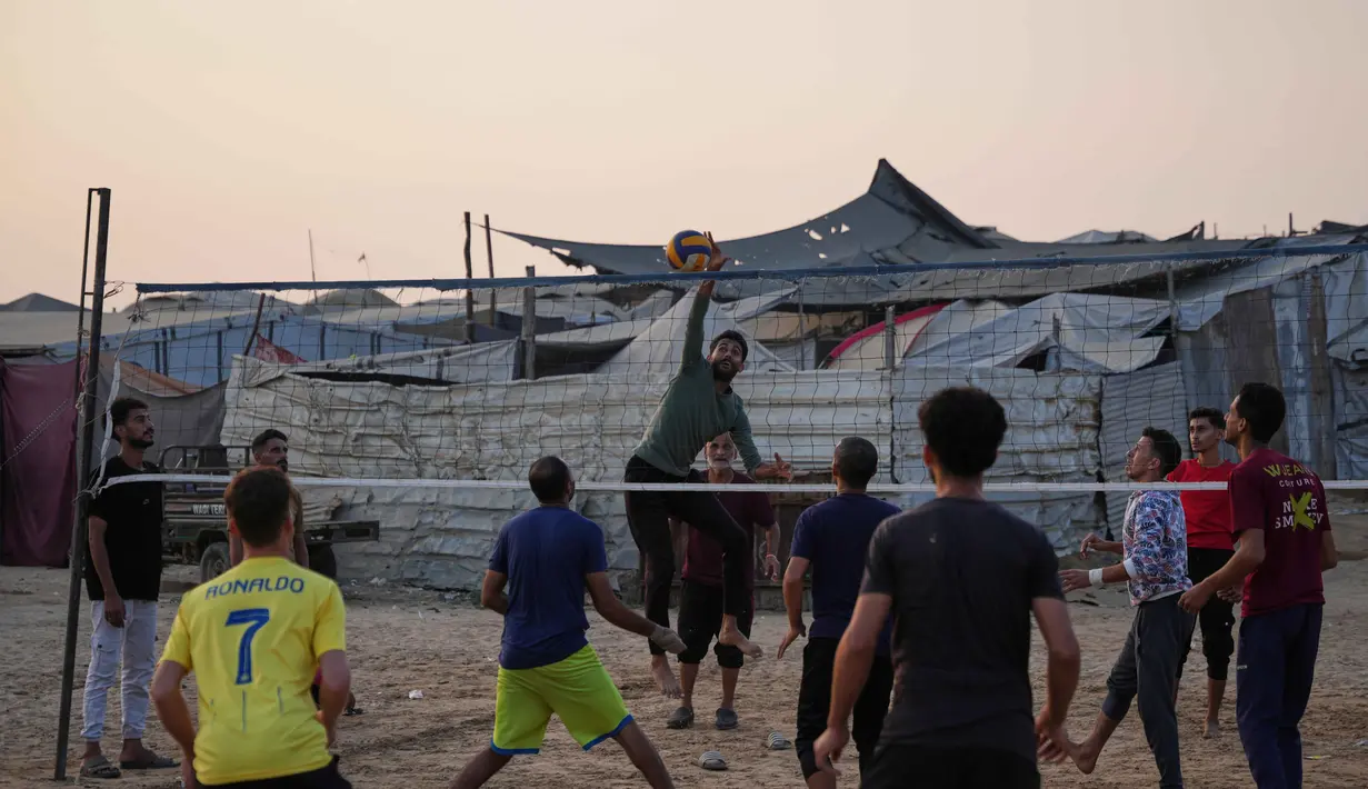 Anak-anak muda Palestina bermain voli di kamp tenda pengungsian di Zawayda, Jalur Gaza tengah, Selasa 4 November 2025. Sejumlah komunitas internasional terus memantau perkembangan gencatan senjata dengan keprihatinan mendalam. (AP Photo/Abdel Kareem Hana)